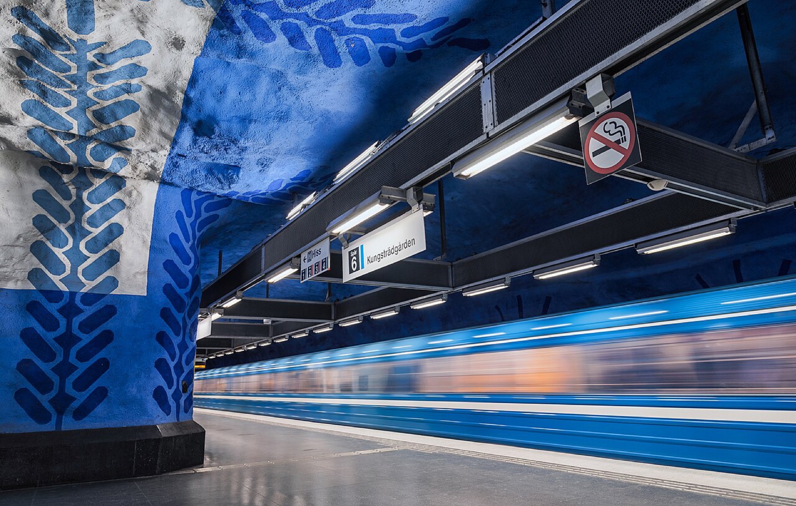 Blue leaf patterns by Per Olof Ultvedt above a passing train at T-Centralen